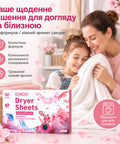 Мама з дитиною тримають мʼякий рушник поруч з коробкою серветок для сушильної машини Kelee